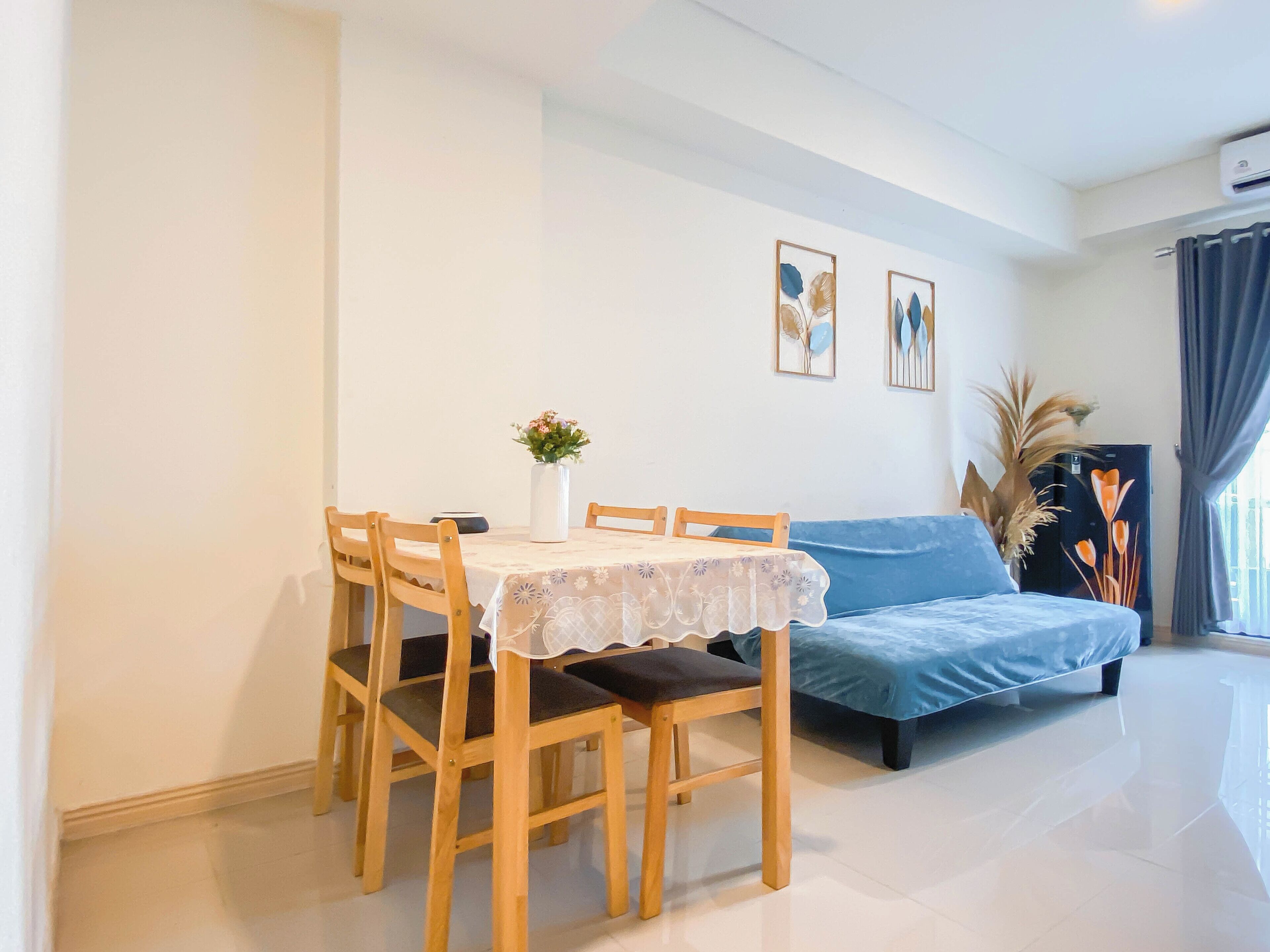 A dining area with a table and chairs, a sofa, and a wall-mounted air conditioner.