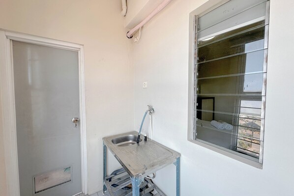 A small bathroom with a window, a sink, and a door.