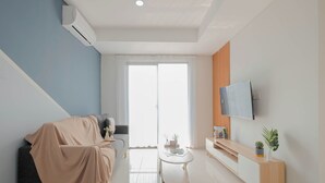 Una sala de estar moderna con un sofá, una mesa de centro, un televisor y una planta.