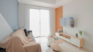 Una sala de estar moderna con un sofá, una mesa de centro, un televisor y un gran ventanal corredizo.