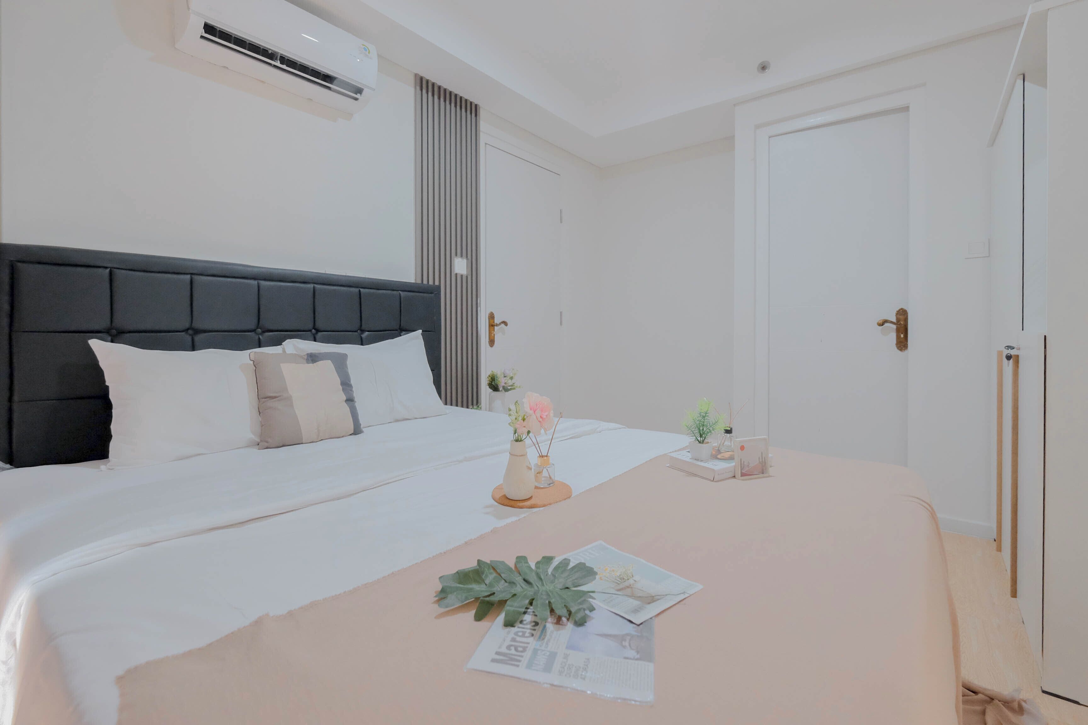 A neatly arranged bedroom with a bed, bedside table, and a small plant.