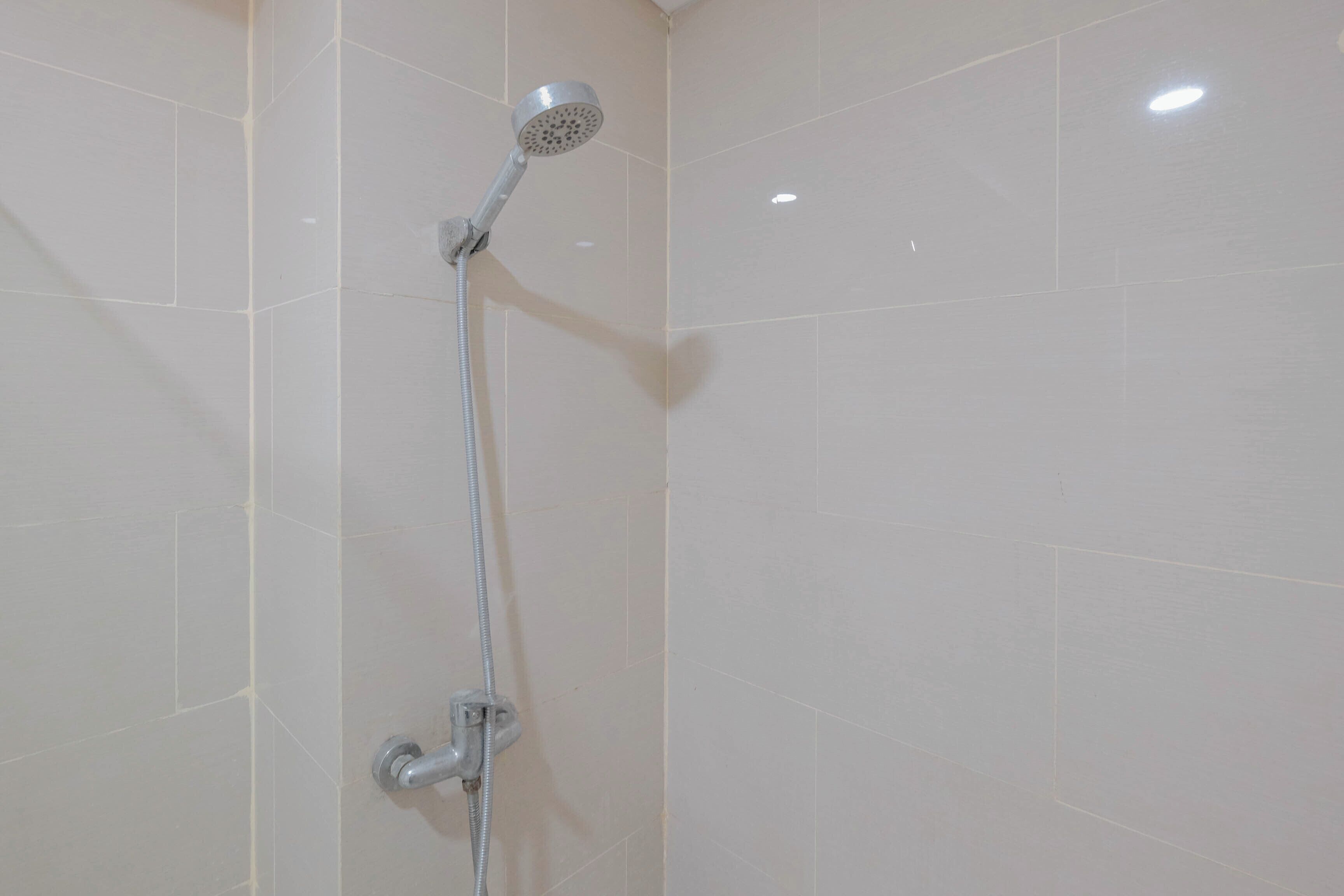 A shower with a handheld showerhead mounted on a wall.