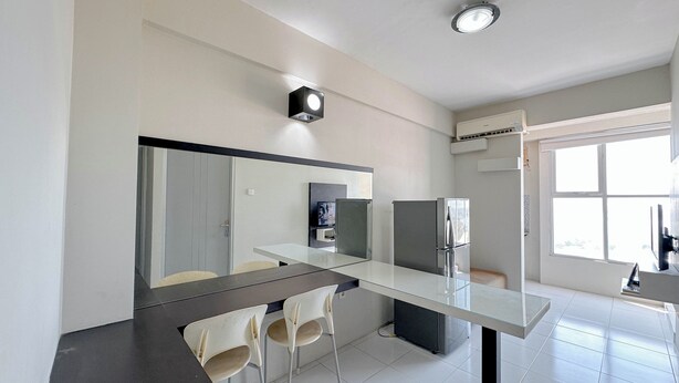 Une cuisine moderne avec une table à manger en verre, des chaises blanches et un réfrigérateur encastré.