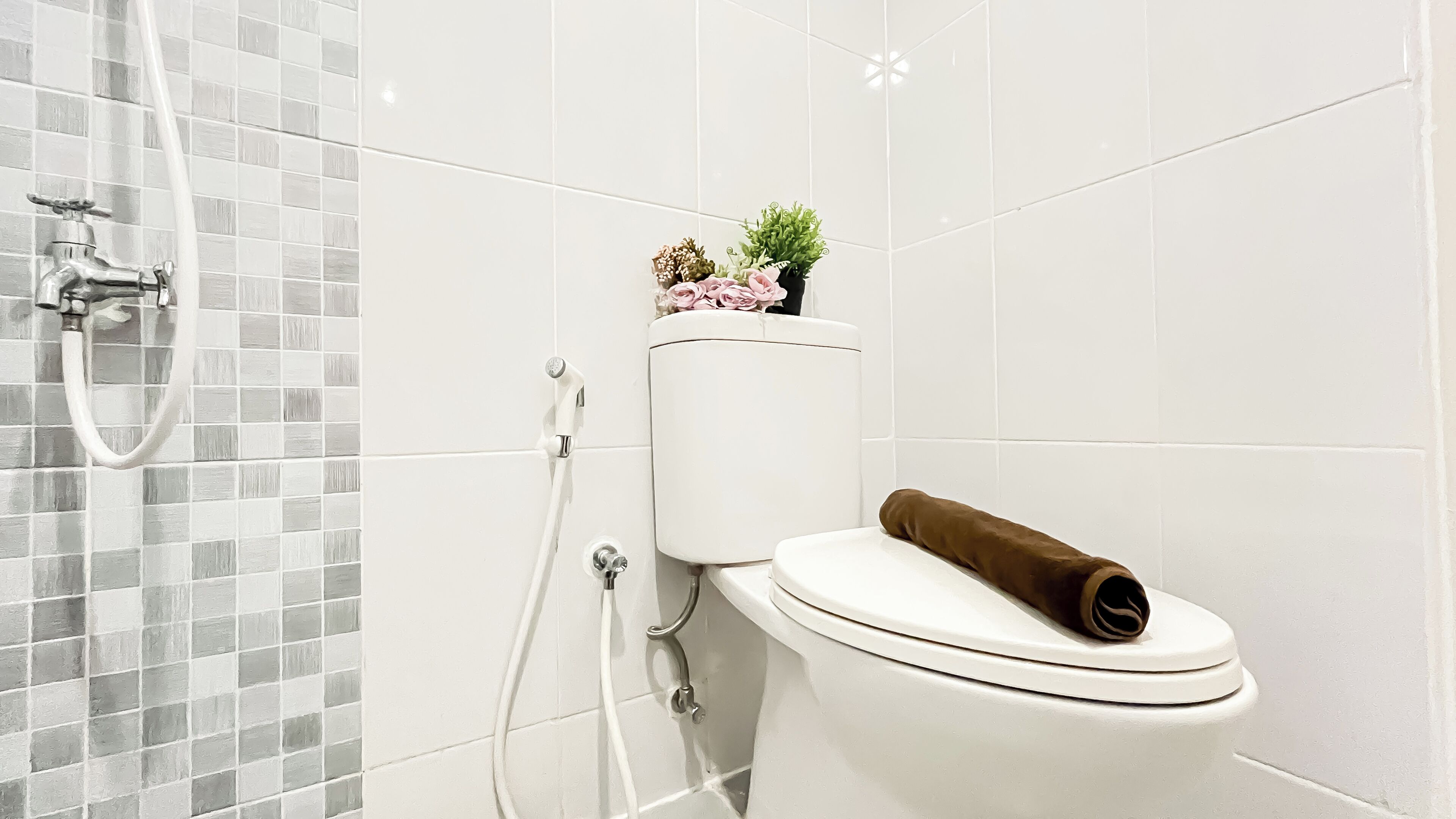 Un bagno con il water, una doccia e un portasciugamani per carta igienica.