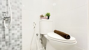 A bathroom with a toilet, a shower, and a toilet paper holder.