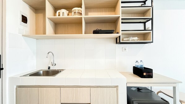 Une cuisine moderne dotée d’un évier en acier inoxydable, d’un dosseret de carrelage blanc, de meubles en bois et d’un plan de travail noir.