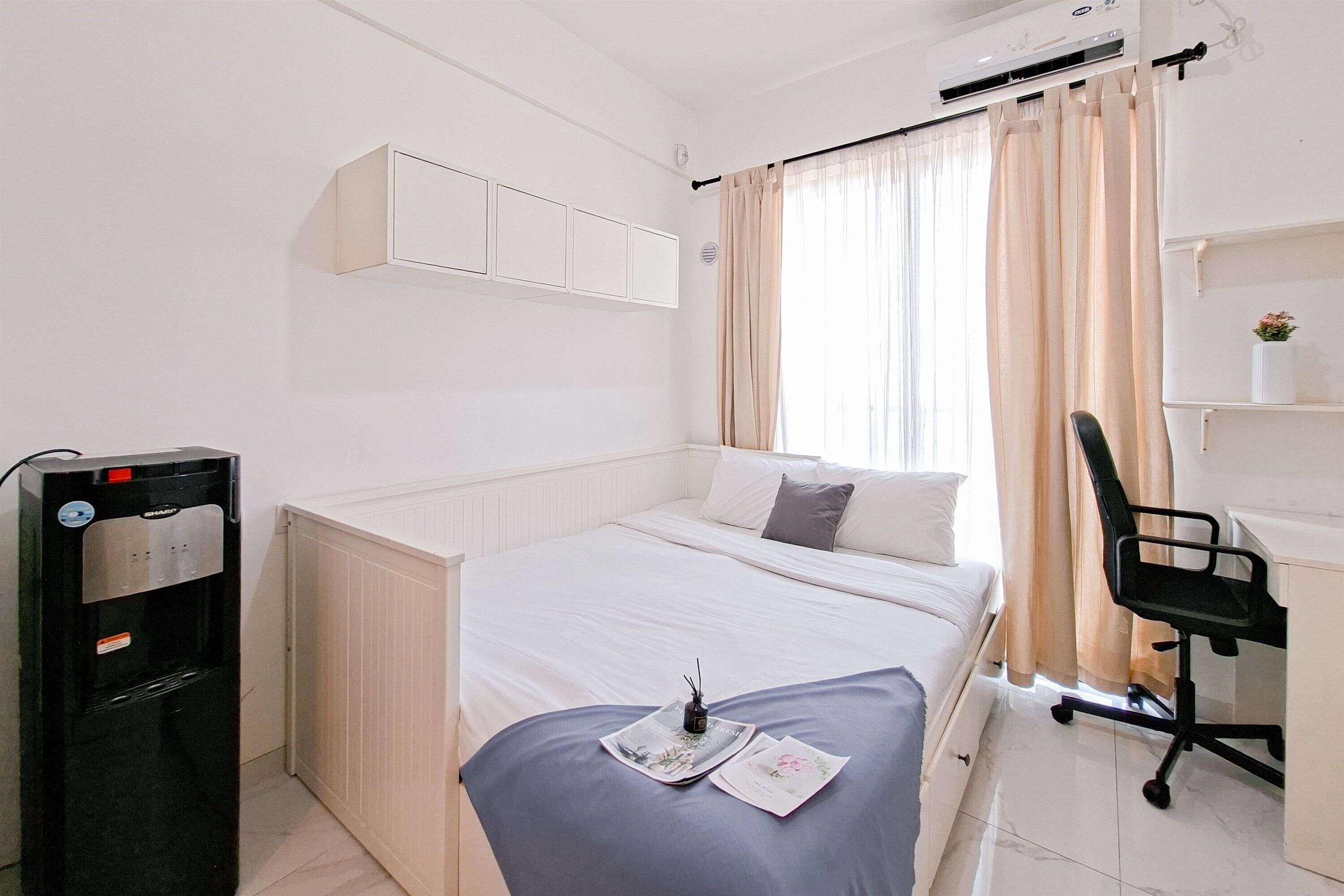 A small, neatly arranged bedroom with a bed, a desk, a chair, and a radiator.