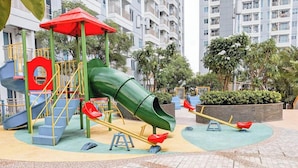 Un’area giochi con uno scivolo verde, altalene e una giostra.