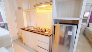 Una cucina compatta con frigorifero in acciaio inox, lavello e pensili in legno.