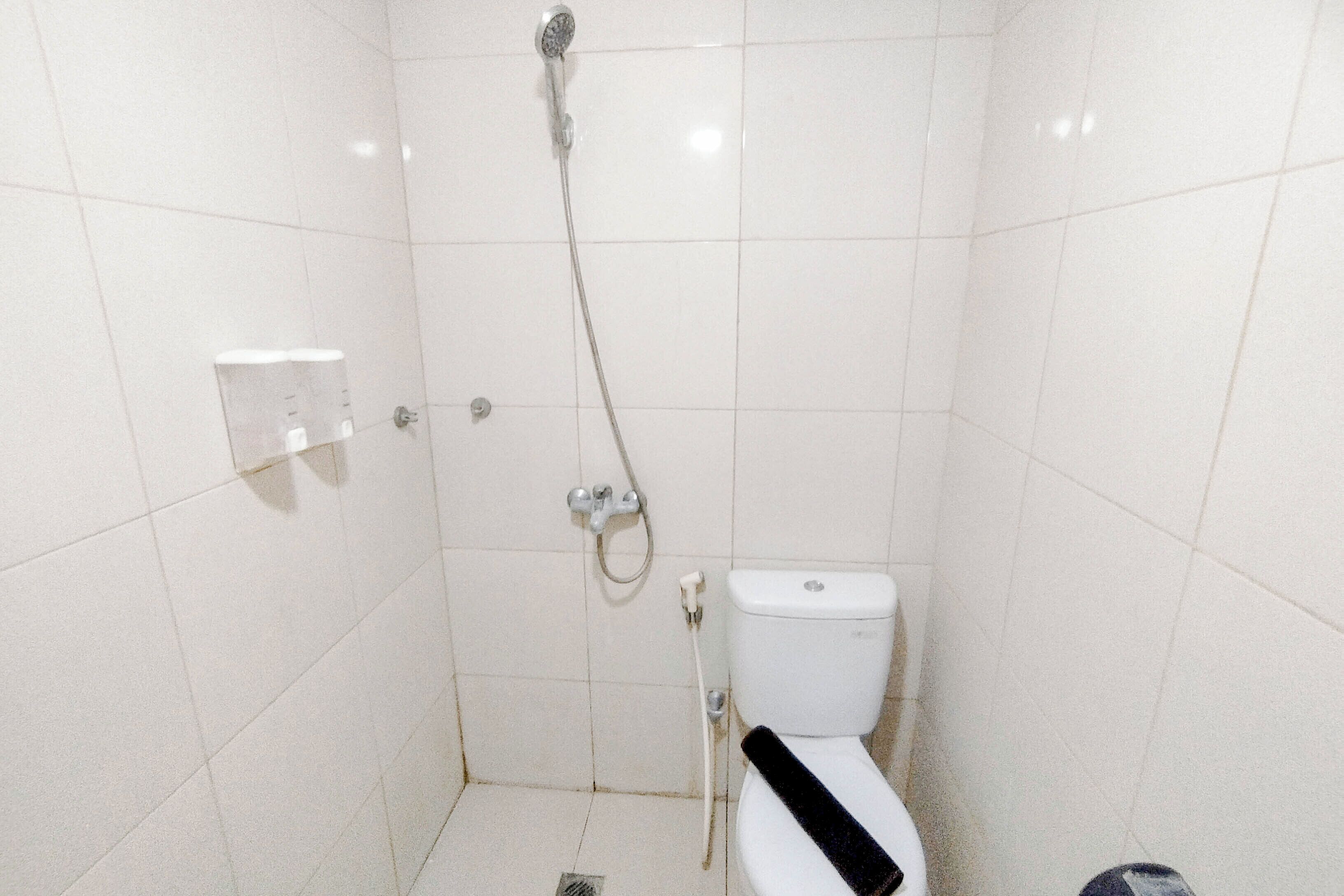 A small, tiled bathroom with a toilet, a shower, and a hand dryer.