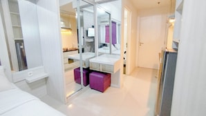 Un bagno moderno con cabina doccia in vetro, un lavandino bianco e una panca viola.