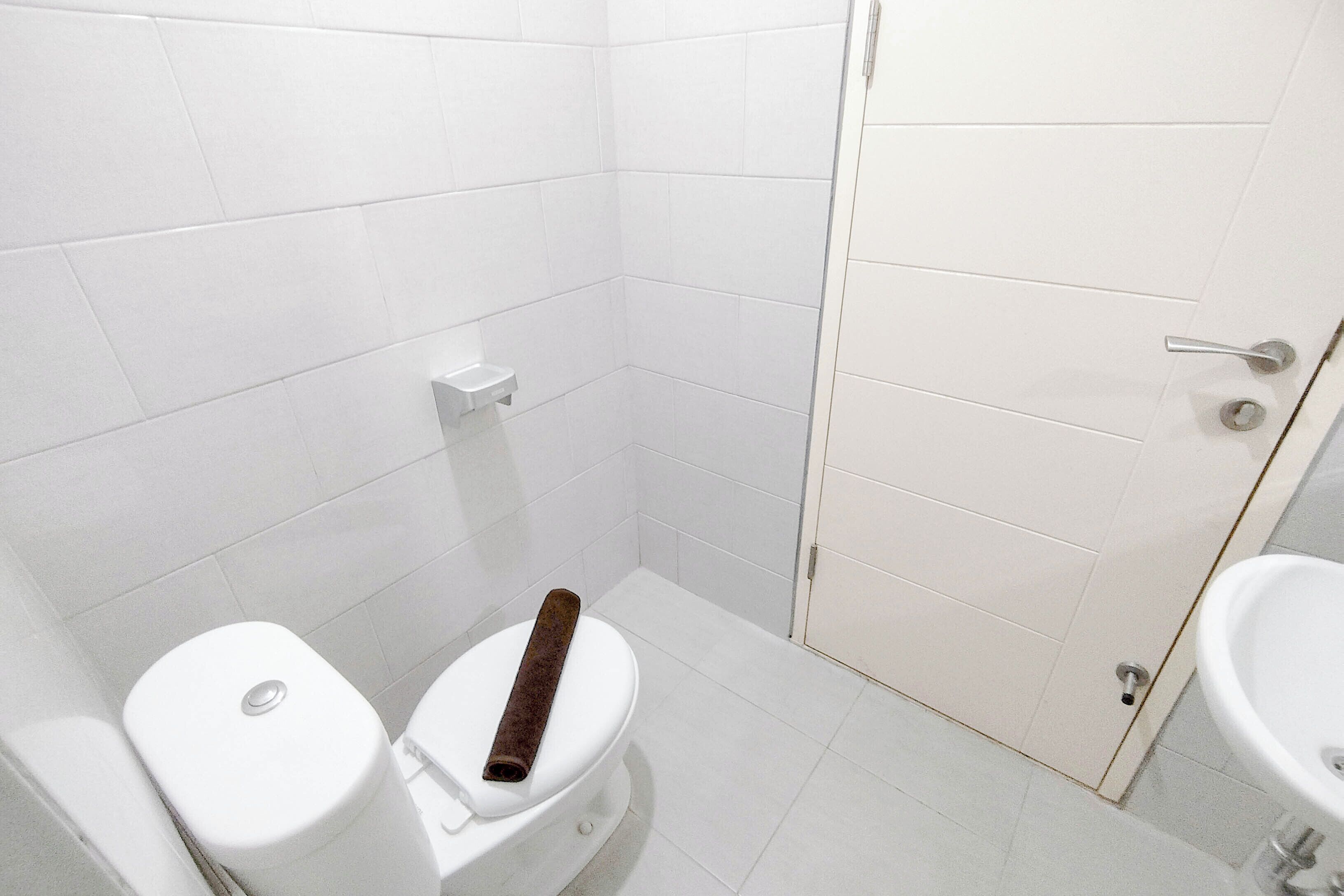 Une petite salle de bain propre, avec des carreaux blancs, des toilettes, un bidet et un lavabo.