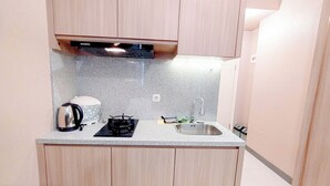 Een compacte keuken met houten kastjes, een granieten aanrecht, een gasfornuis, een waterkoker en een spoelbak.