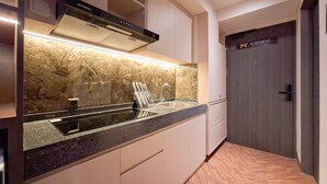 Een moderne keuken met een marmeren spatwand, roestvrijstalen apparatuur en een houten vloer.