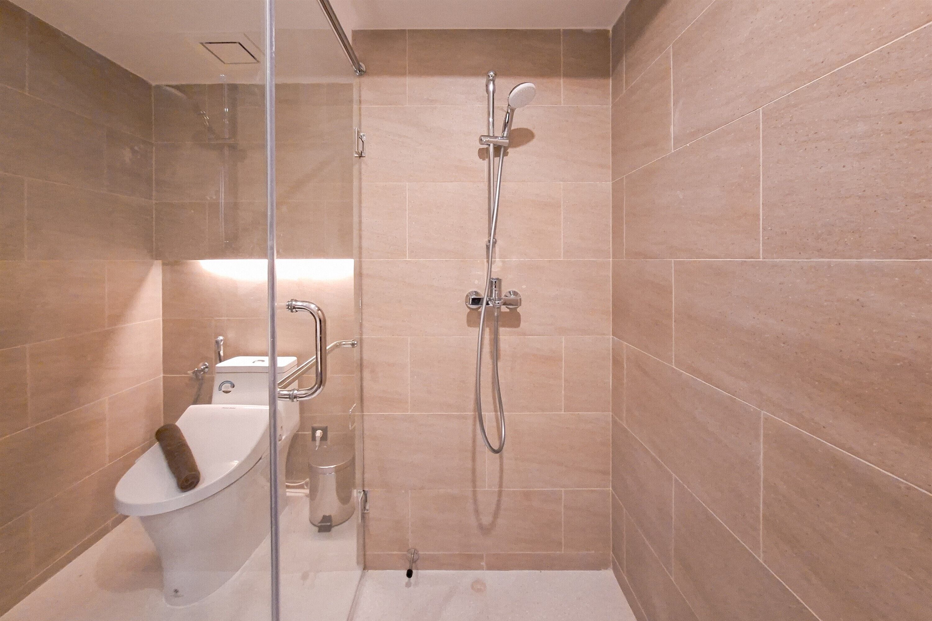 Un bagno moderno con doccia vetro e vasca da bagno bianca, con piastrelle color crema.