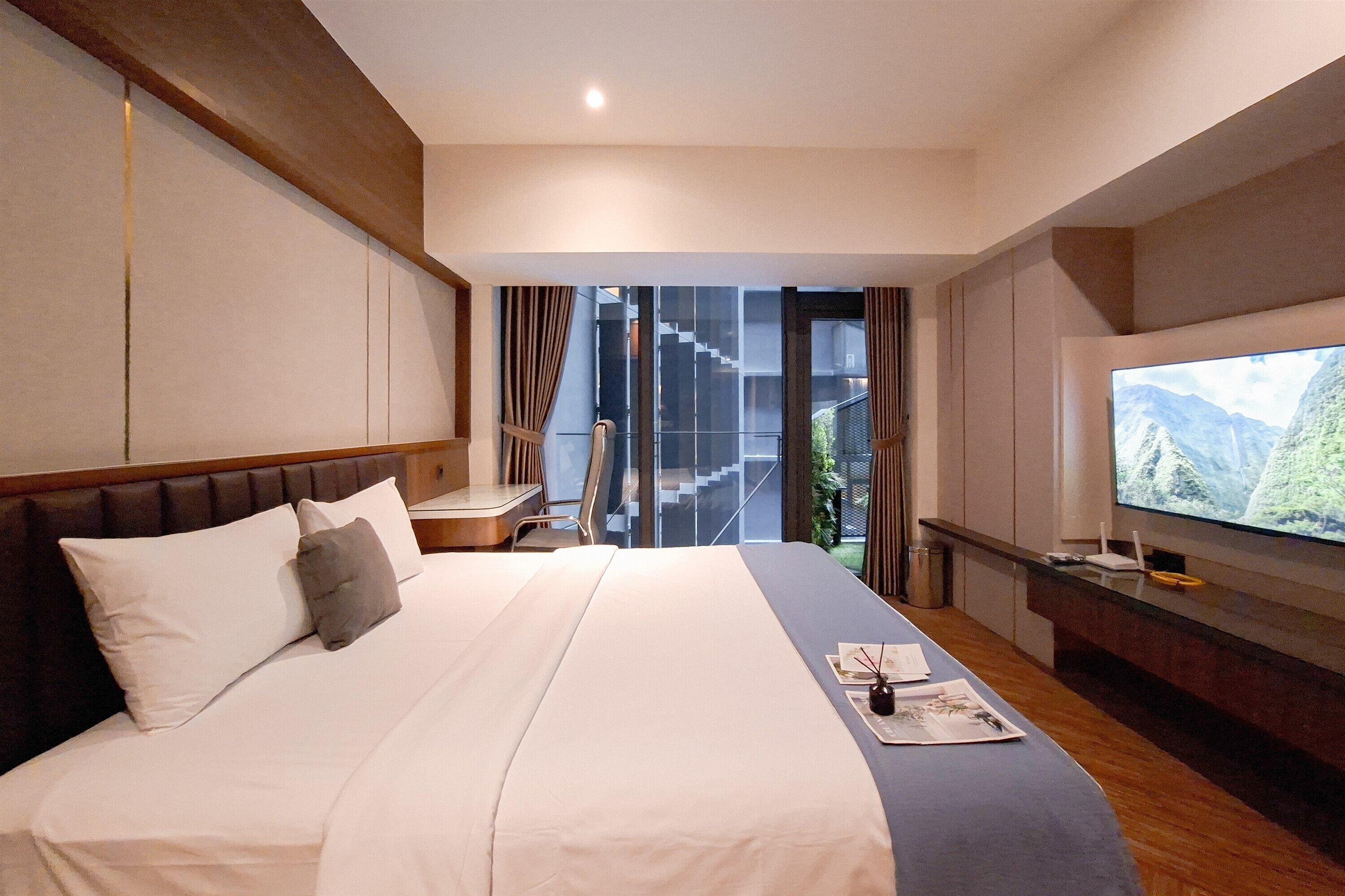 A hotel room with a large bed, a desk, and a television.