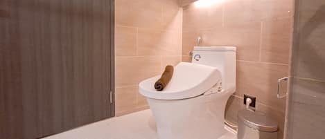 A modern bathroom with a toilet, a trash bin, and a towel on the toilet seat.