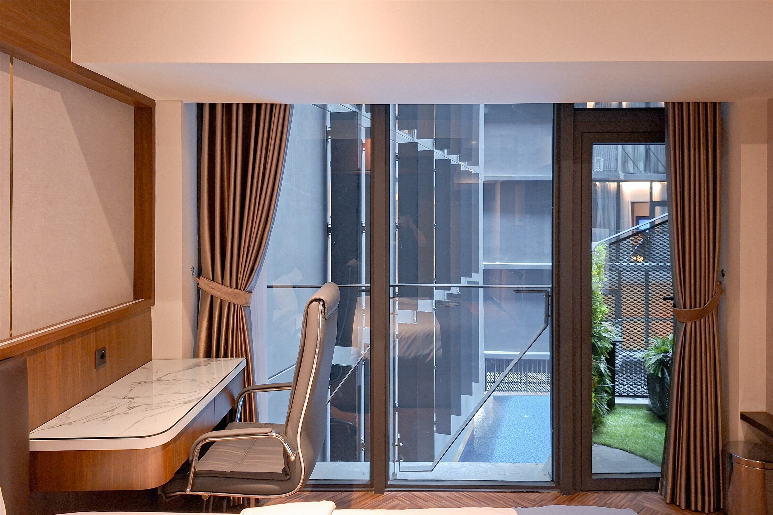 A modern room with a sliding glass door leading to a balcony, a wooden desk, and a chair.