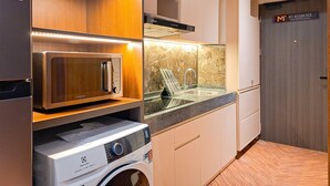 Een moderne keuken met een ingebouwde magnetron, een wasmachine en een spoelbak met glazen blad.