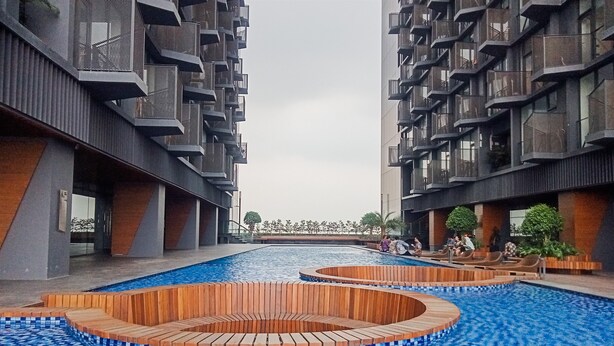 Een modern gebouw met een centraal gelegen zwembad, houten zitplaatsen en een betegelde vloer.