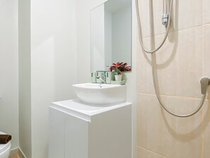 Une salle de bain avec un lavabo blanc, un miroir, une douche et des toilettes.