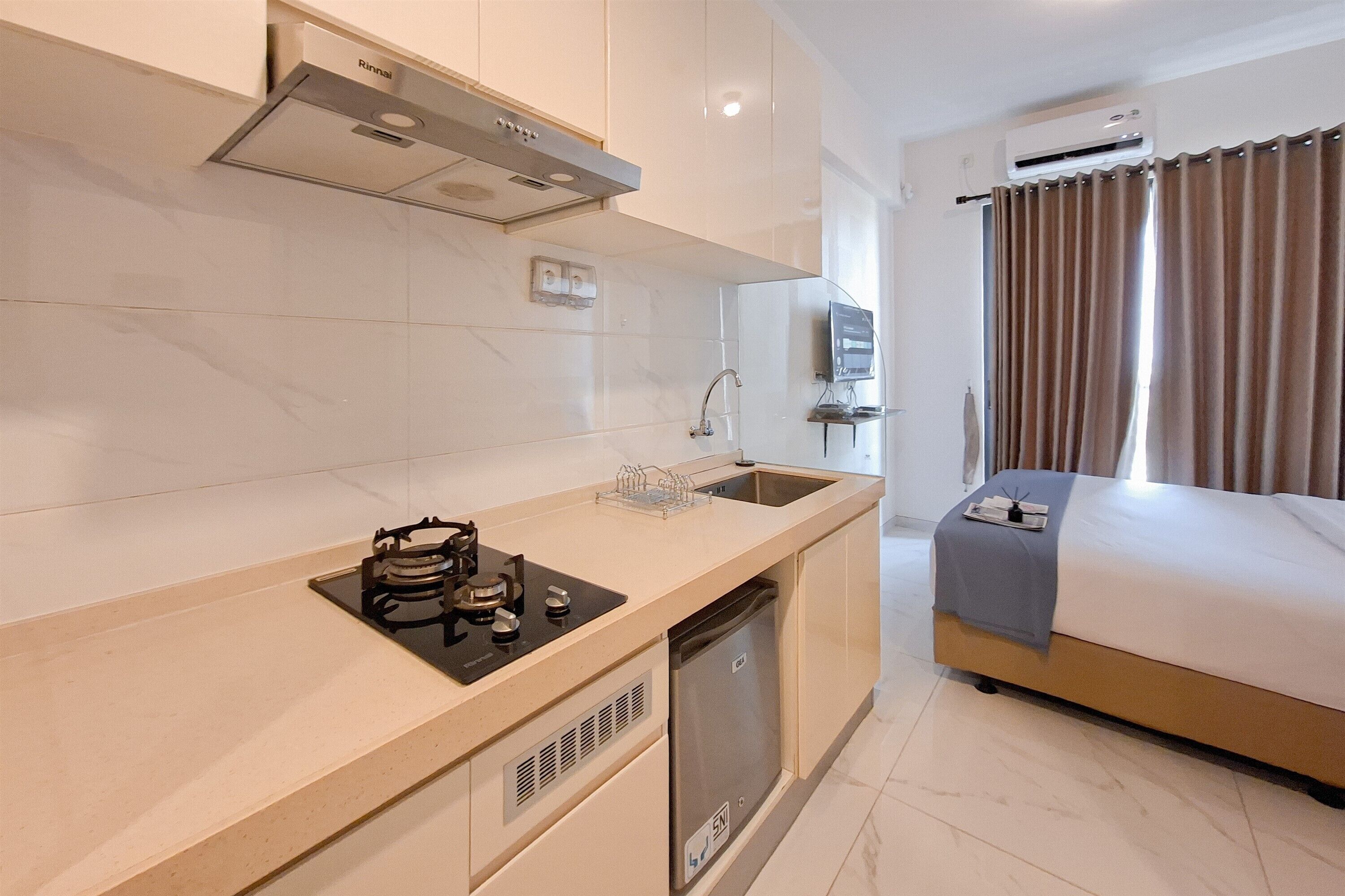 A modern hotel room with a kitchenette, a bed, and a bathroom.