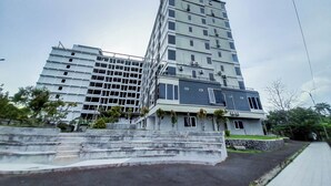A multi-story hotel with a modern design, featuring a prominent staircase leading to the entrance. - Spacious 2Br At Green Park Yogyakarta Apartment (Depok)