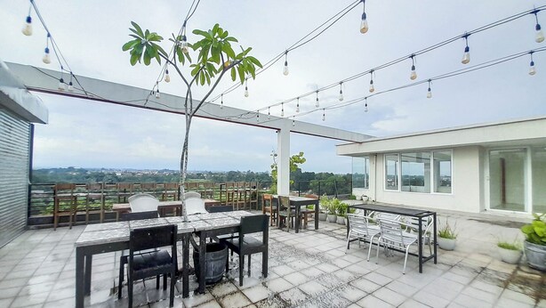 An outdoor patio with a table and chairs, string lights, and potted plants. - Spacious 2Br At Green Park Yogyakarta Apartment (Depok)