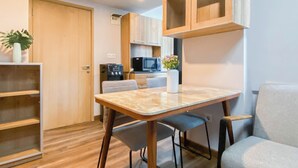 A compact kitchen with a microwave, refrigerator, and a small dining area with a table and chairs. - Simple 1Br Near Dian Harapan School At Apartment Meikarta (Cikarang)