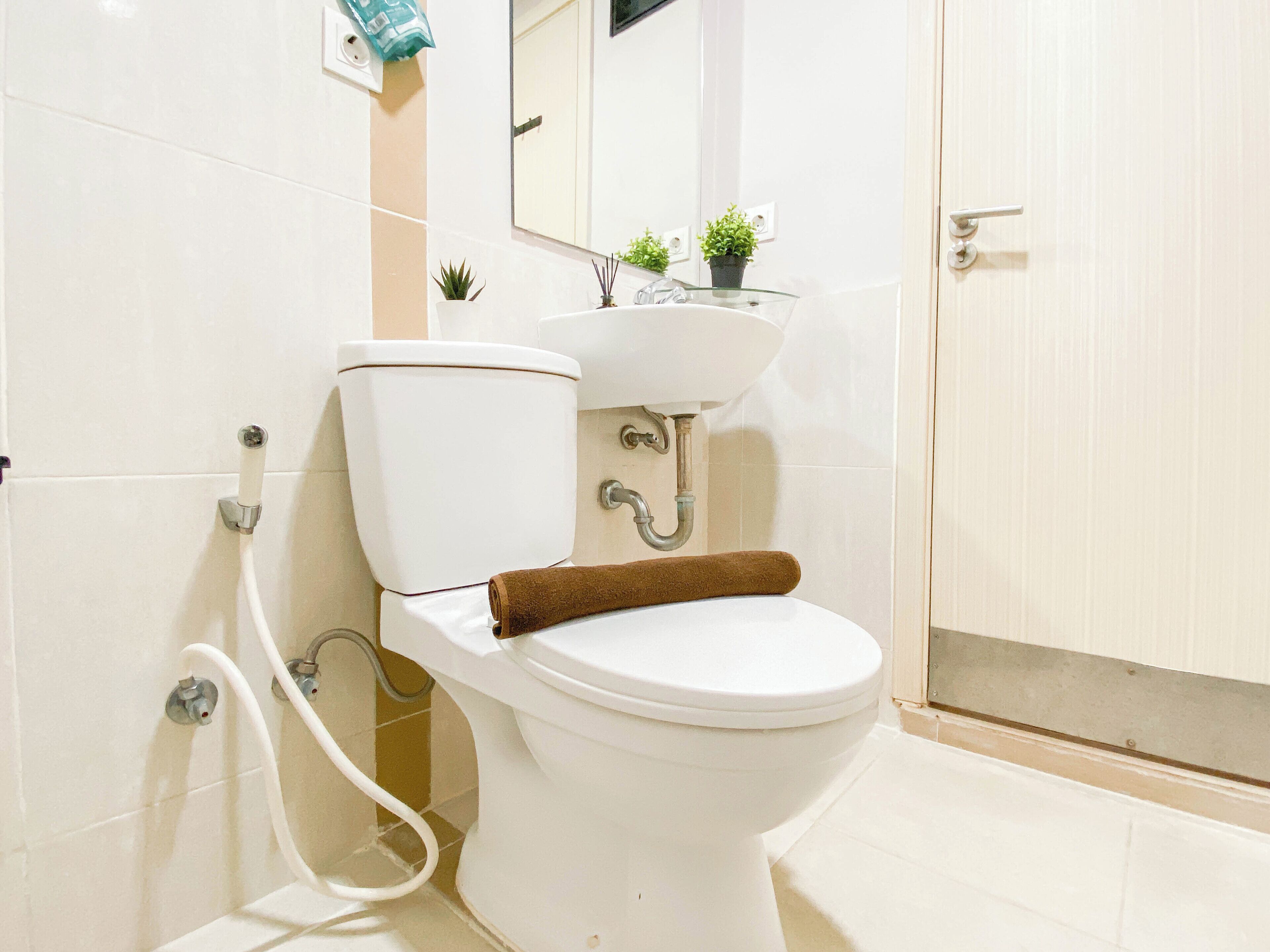 A bathroom with a white toilet, a glass sink, and a mirror above the sink.