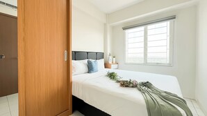 Ein Schlafzimmer mit einem Bett, einem Nachttisch, einem Fenster und einem Holzschrank.