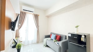 Ein modernes Wohnzimmer mit einem grauen Sofa, einer schwarzen Unterhaltungsecke und einem großen Fenster mit Vorhängen.