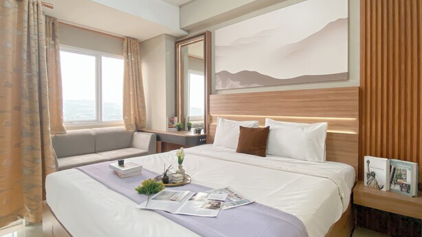 Camera d'albergo con un letto grande, un divano, una scrivania e una finestra con tende.