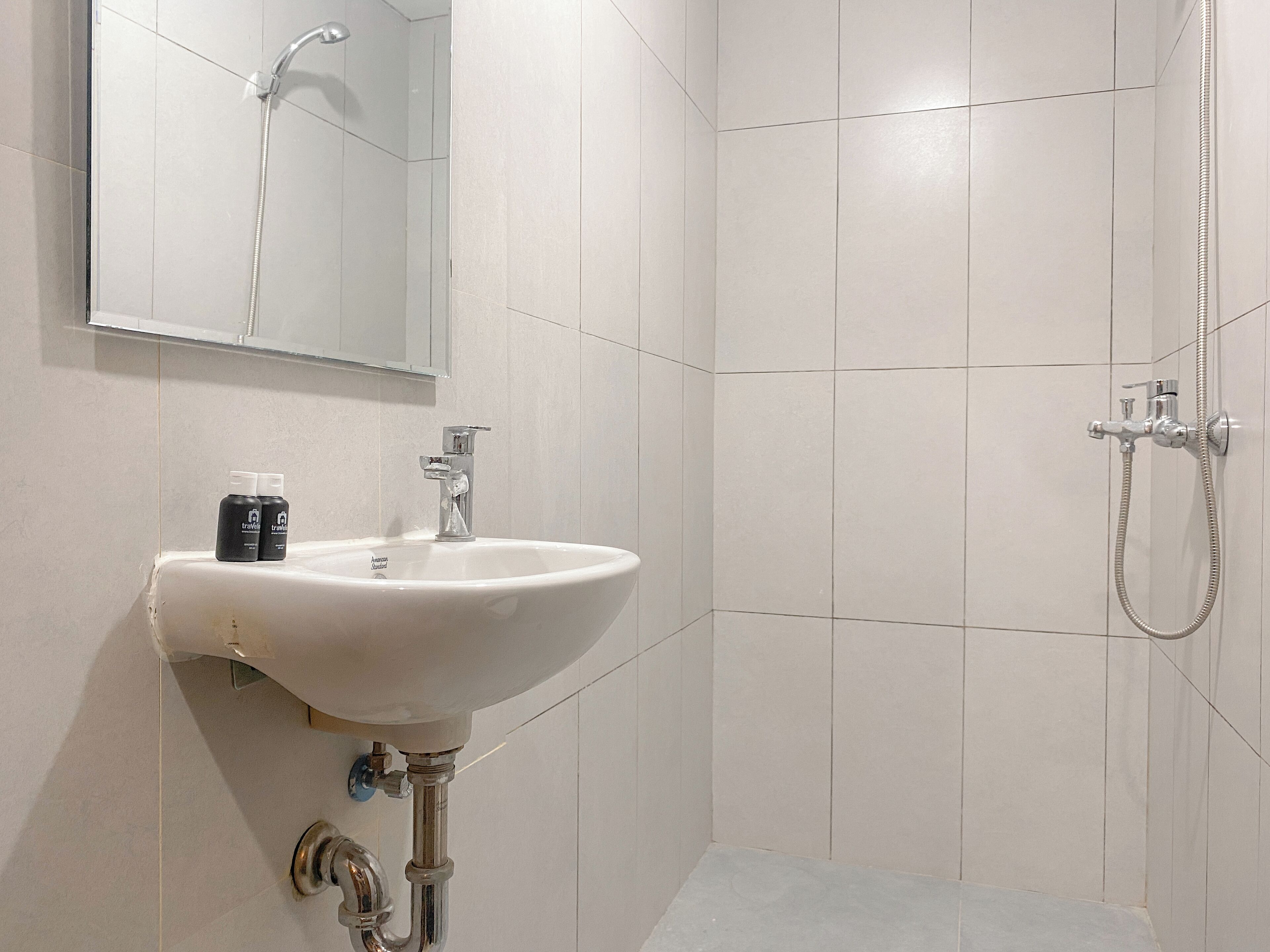 Un baño con lavamanos blanco, espejo y ducha.