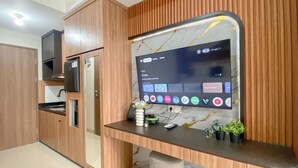 Una cucina moderna con mobili in legno, forno integrato e un grande schermo piatto montato a parete.