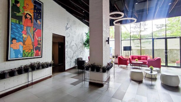 A spacious lobby with a large colorful mural, modern seating, and a view of greenery outside. - Modern 2Br Apartment At Cordova Edupartment Semarang (Semarang)
