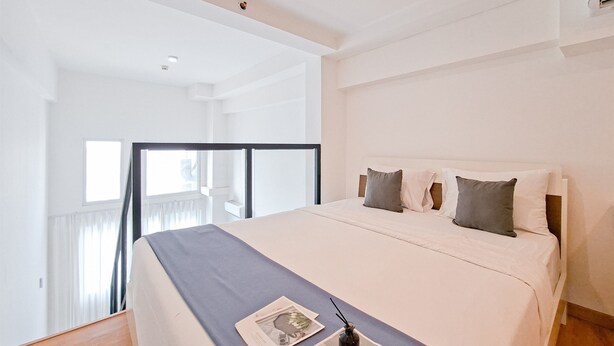 A modern bedroom with a large bed, a balcony, and a view of the city.