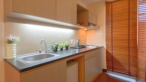 A modern kitchen with a double sink, a built-in oven, and a window with blinds. - Good Deal 1Br Apartment At Marina Ancol (Jakarta)