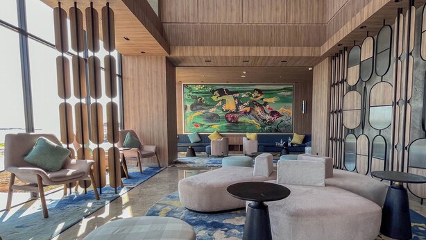 A modern lobby with a large mural, seating areas, and a unique wall design. - Modern Scandinavian Studio At Delft Ciputra Makassar Apartment (Makassar)