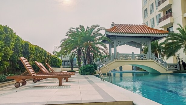 Un espace piscine comprenant des chaises longues, un gazebo et un pont au-dessus de la piscine.