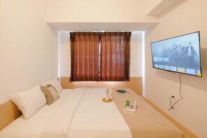 A modern hotel room with a large bed, a flat-screen TV mounted on the wall, and a window with curtains. - 2Br Near Shopping Hub At Tokyo Riverside Pik 2 Apartment (Teluknaga)