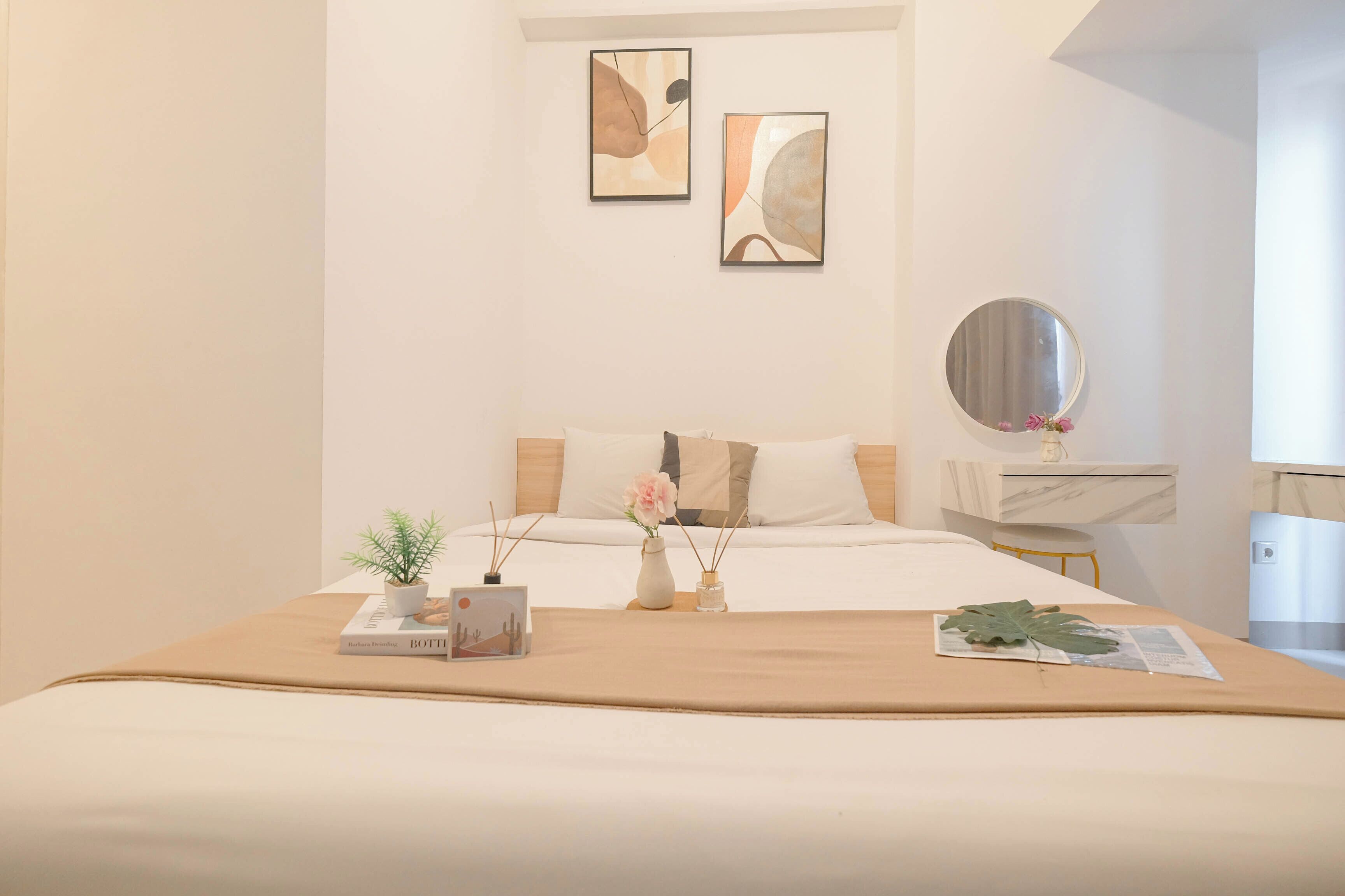 Une chambre à coucher bien rangée, avec un lit, une table de chevet et un miroir.