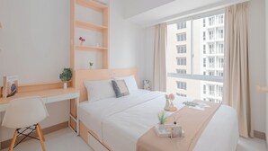 Hotelkamer met een bed, een bureau, een stoel, een raam met gordijnen en uitzicht op een gebouw.