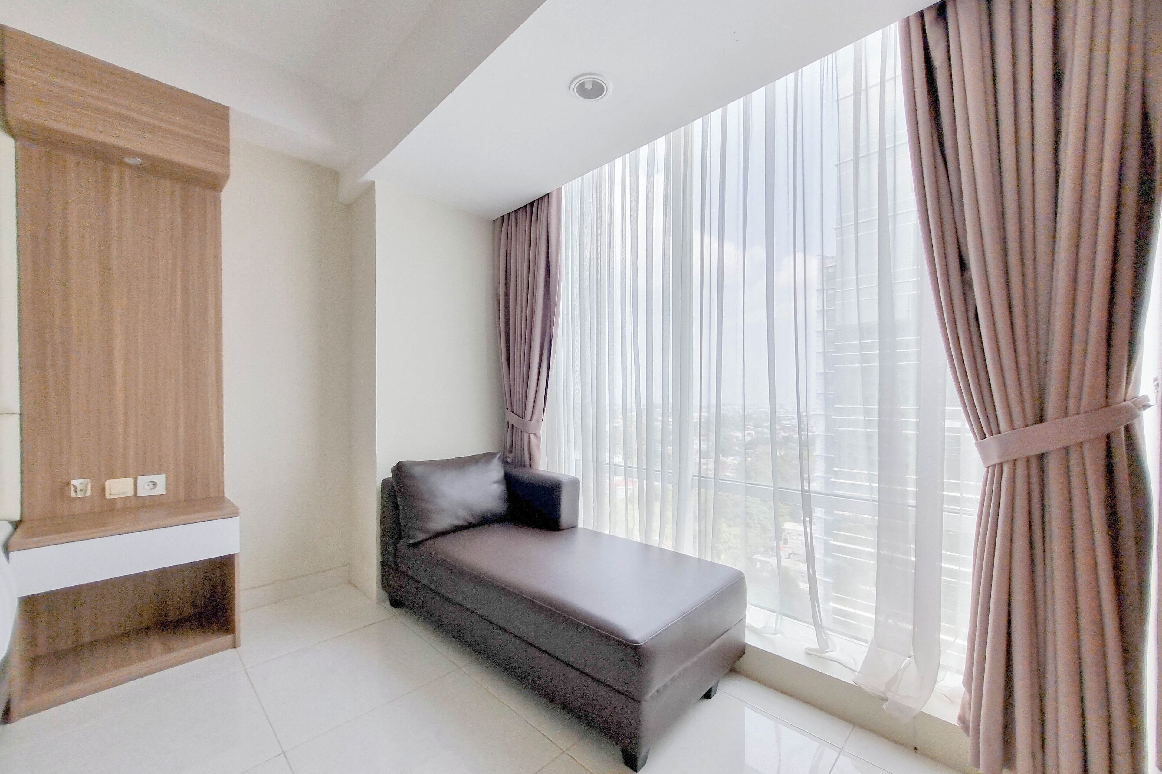 Una sala de estar moderna con un sofá, un aparador de madera y ventanas grandes con cortinas.