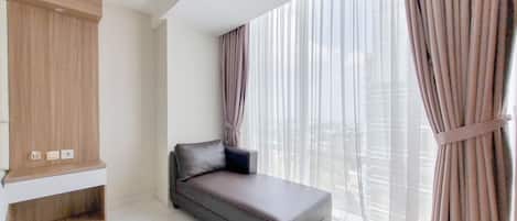 Una sala de estar moderna con un sofá, un aparador de madera y ventanas grandes con cortinas.