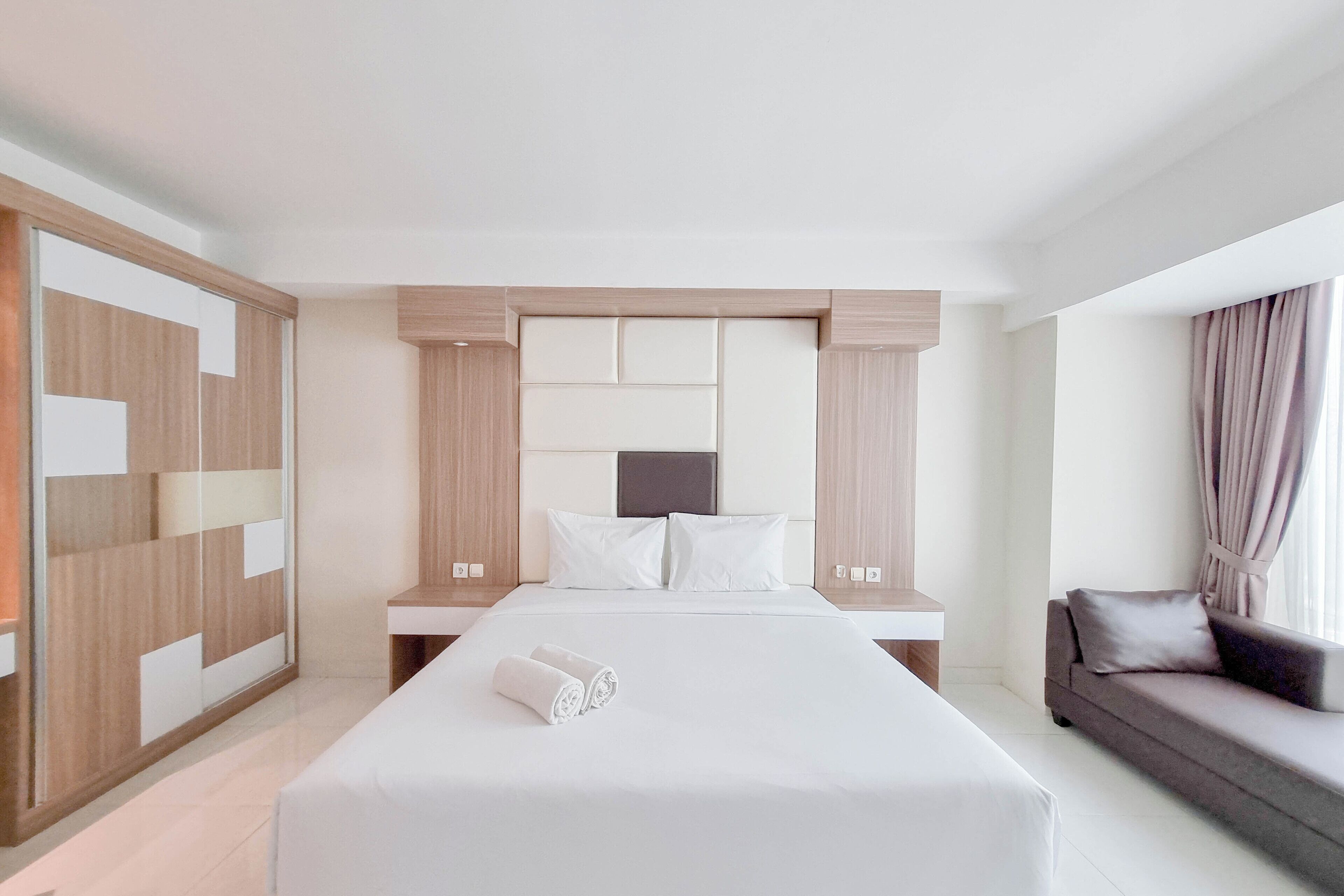 Ein modernes Hotelzimmer mit einem großen Bett, einer Sitzecke und einem begehbaren Kleiderschrank.