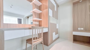 A modern room with a wooden chair, a built-in desk, and a wardrobe with a mirror. - Tidy Studio At Mataram City Apartment (Ngaglik)