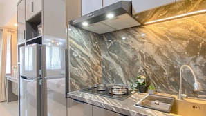 A modern kitchen with a marble backsplash, stainless steel appliances, and a built-in sink. - Best Studio Apartment At Gateway Park Lrt City Jatibening (Bekasi)