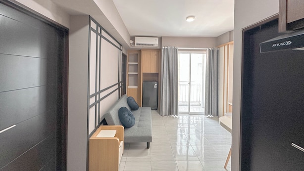 Ein moderner Hotelkorridor mit einer Couch, einem kleinen Tisch, einem Kühlschrank und einer Klimaanlage.