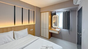 Ein Hotelzimmer mit einem Bett, einem Kleiderschrank, einem Schminktisch mit Spiegel und einer Klimaanlage.